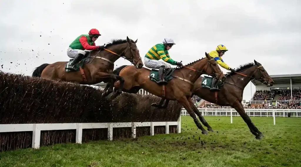 Paarden en jockeys die over een grote Aintree-hindernis springen tijdens de Grand National